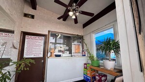 A Palm Leaf Motel reception area with a ceiling fan, a window with a view, a door, and a counter with a menu. - King Bed Non-Smoking (Ashland, VA)