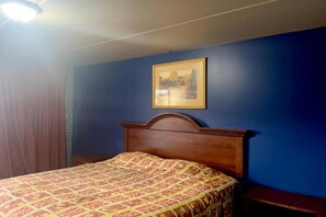 A room with a bed, a framed picture on the wall, and a wooden headboard. - King Bed|Smoking|Chicago (Chicago IL)