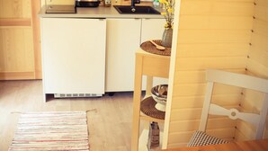 Ett kompakt kök med en inbyggd ugn, en diskho och en liten matplats med ett bord och en stol.