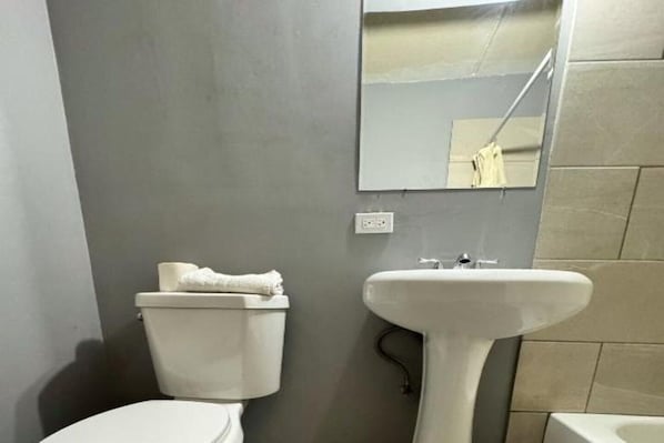 A bathroom with a toilet, sink, and mirror.