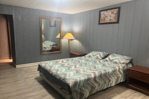 Ein Schlafzimmer mit einem Bett, einem Nachttisch, einer Lampe, einem Spiegel und einer gerahmten Karte an der Wand.