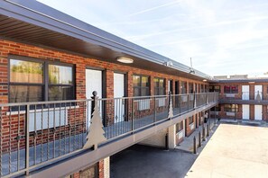 A multi-story building with a brick facade, multiple windows, and a covered walkway.