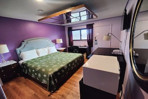 A bedroom with a bed, a desk, a chair, a lamp, and a window. - King Bed Non-Smoking (Chicago)