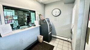 Un'area reception con un bancone, una sveglia, un bancomat e un cestino.