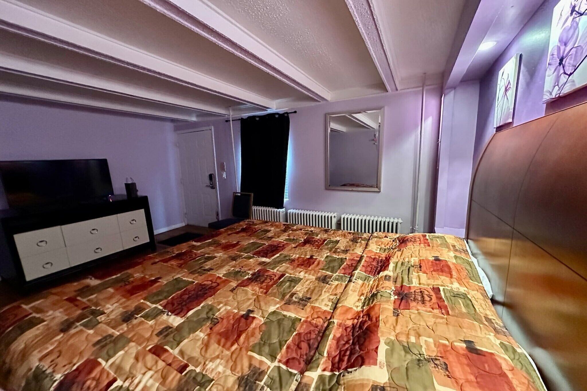 Quarto com cama grande, penteadeira, espelho e radiador.