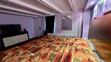 Quarto com cama grande, penteadeira, espelho e radiador.