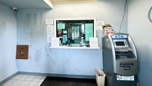 Un bancomat, una finestra con manifesti informativi e una telecamera di sicurezza a parete.