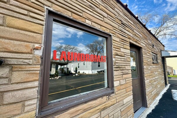 A building with a stone facade and a large window displaying the text 'LAUNDRY MAT'.