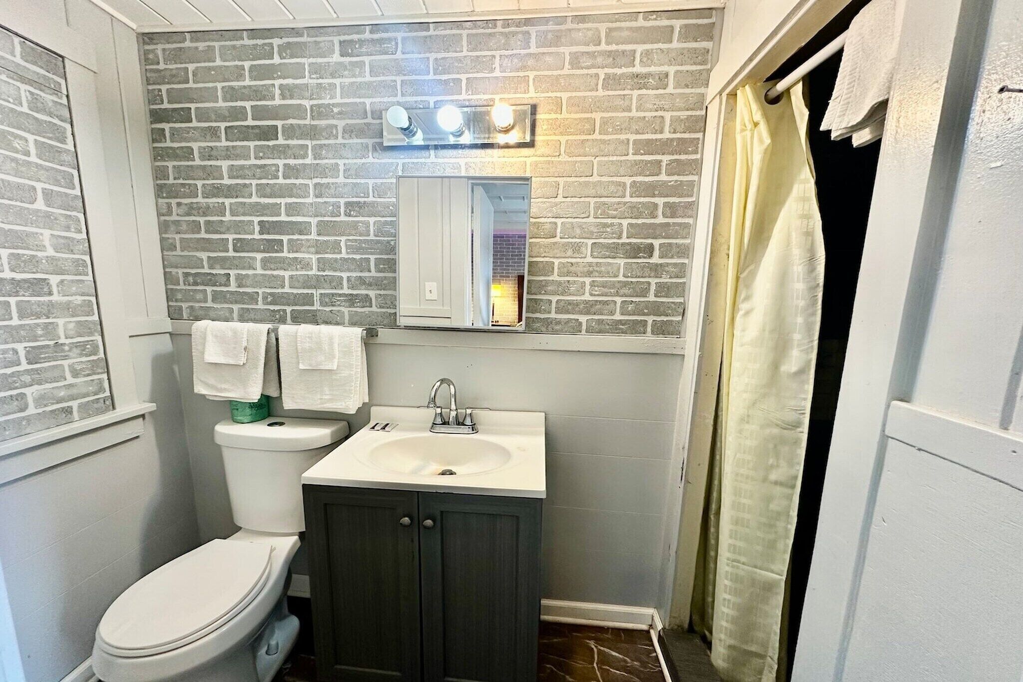Een badkamer met een wit toilet, een wastafel, een spiegel en een douchegordijn.