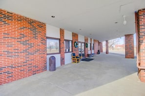 A covered outdoor area with brick walls, windows, and a seating area with chairs.