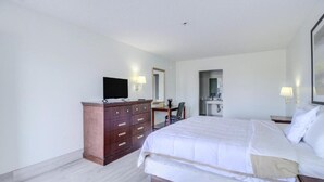 Une chambre d’hôtel avec un lit, une commode, une télévision et un miroir.