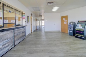 A hallway with a reception desk, a pet fee sign, a no smoking sign, and a vending machine.