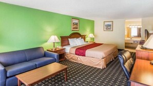 Quarto de hotel com uma cama, um sofá, uma escrivaninha e uma cadeira.