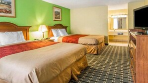 Ein Hotelzimmer mit zwei Betten, einem Fernseher, einem Spiegel und einem Schminktisch.