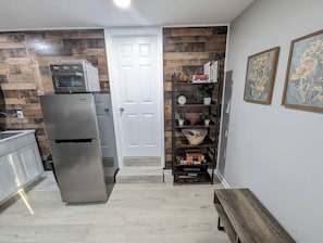 Eine Küche mit Kühlschrank, Backofen und Mikrowelle, Holzvertäfelung, einem Bücherregal mit Büchern und Dekoration sowie einer Tür zu einem anderen Raum.