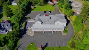 An aerial view of a building with a parking lot, surrounded by greenery.