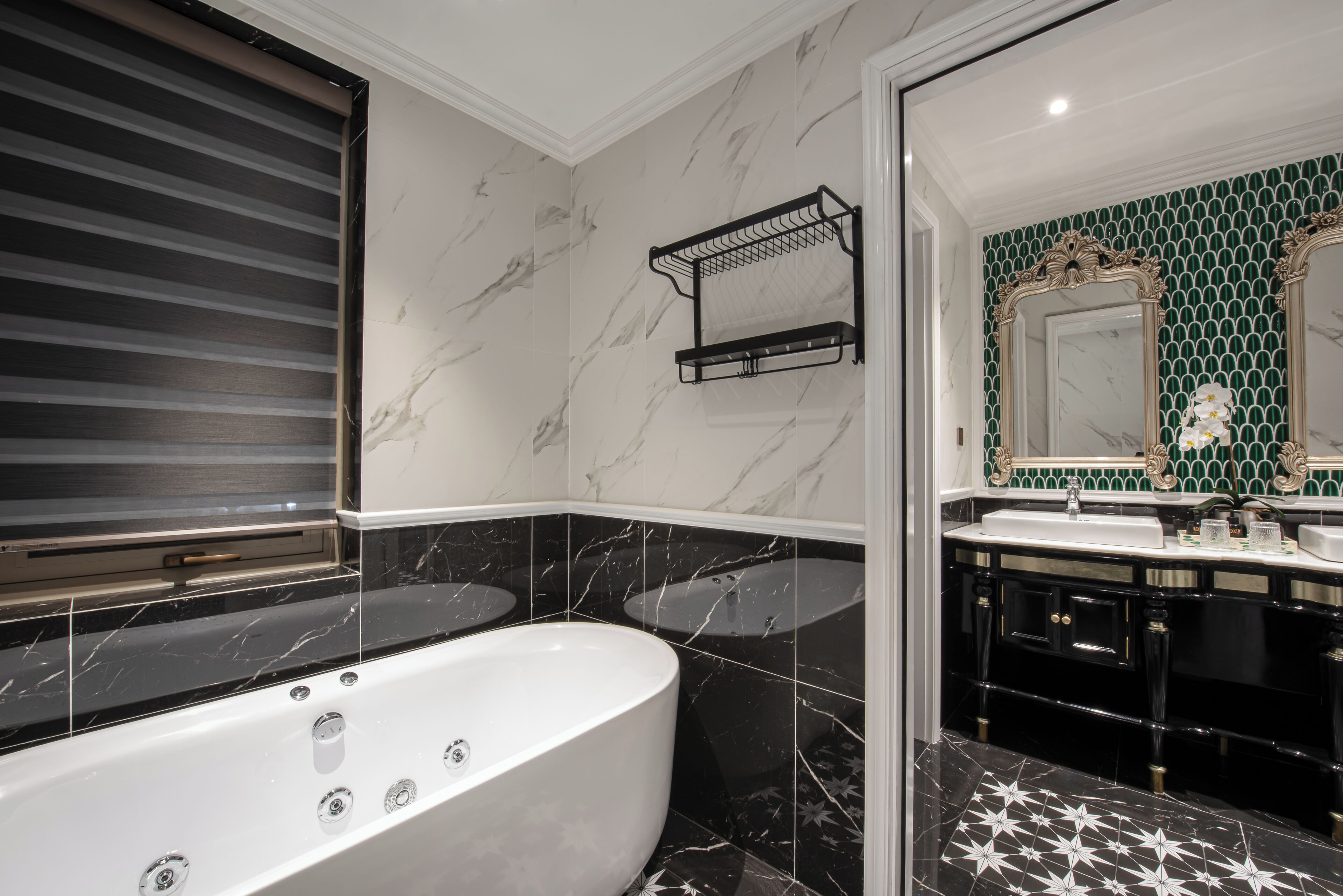 A bathroom with a freestanding bathtub, a black and white tiled floor, a black towel rack, and a green tiled backsplash.