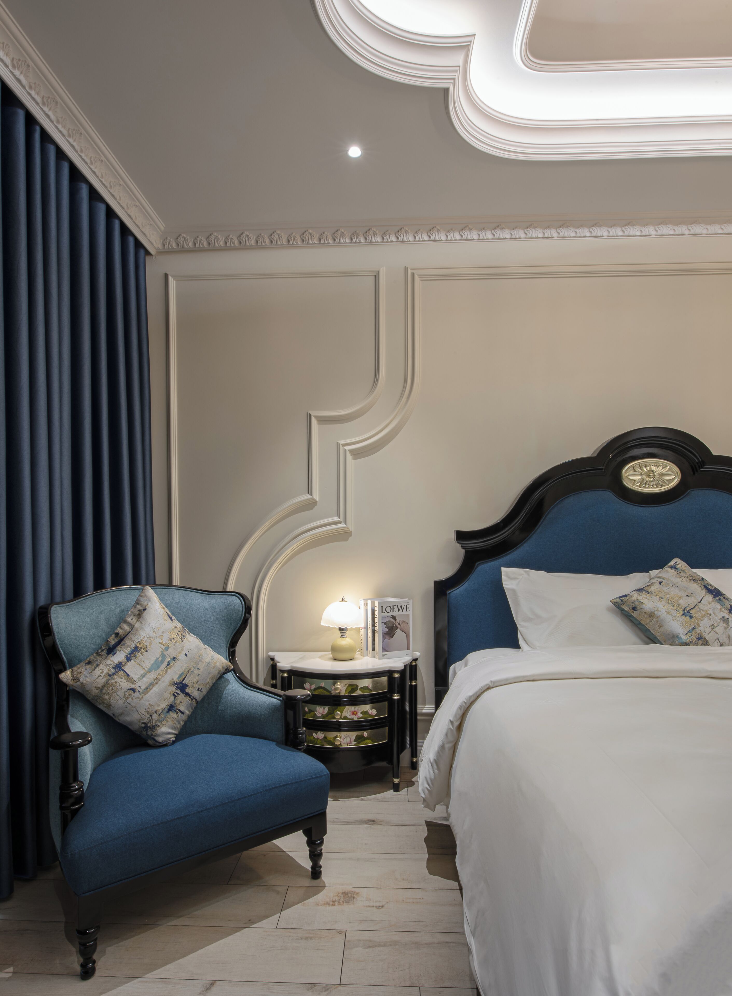 A hotel room with a bed, a chair, a nightstand, and a lamp.