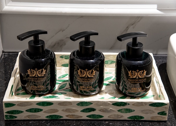 Three black bottles with gold lettering on a tray with a green leaf pattern. - Maison Perla - Luxury Boutique by Hampton Danang (Da Nang)