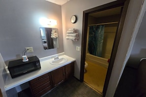Un baño con lavabo, espejo, reloj y toallas.