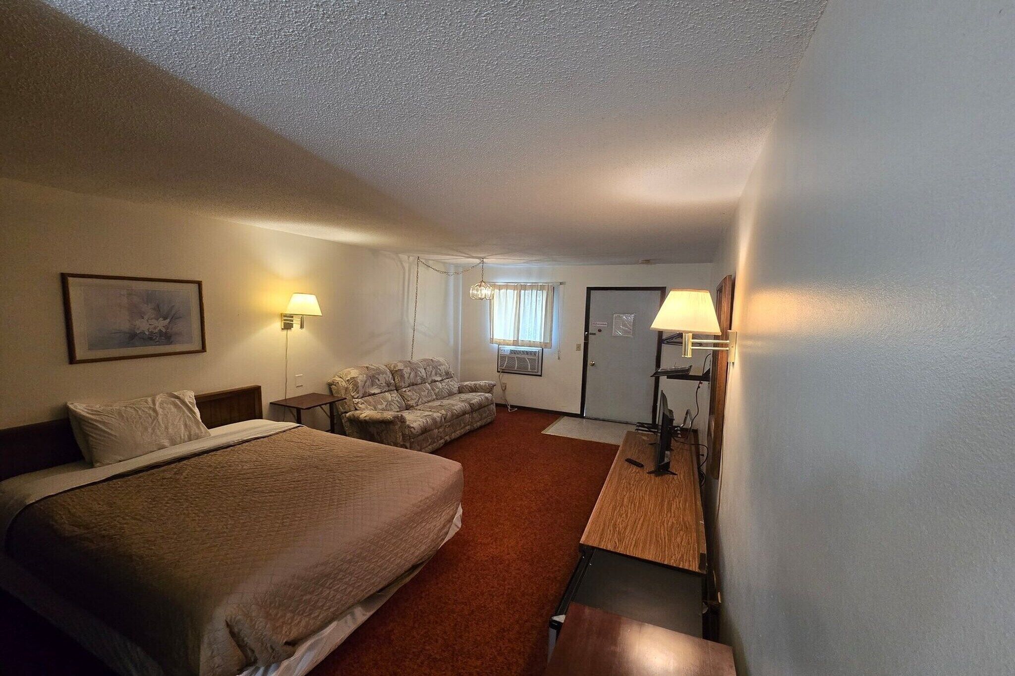 Una habitación de hotel con una cama grande, un sofá, un escritorio y dos lámparas de pared.