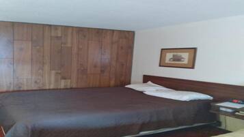 A single bed with a wooden headboard, a bedside table with a lamp, and a framed picture on the wall.