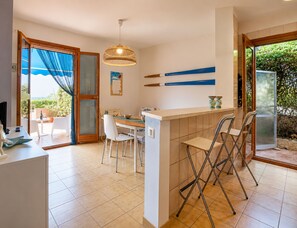A modern kitchen with a dining area, a bar, and a sliding glass door leading to an outdoor patio. - Vacation Home in Marina Di Ragusa with 3 bedrooms sleeps 6 (Marina Di Ragusa)