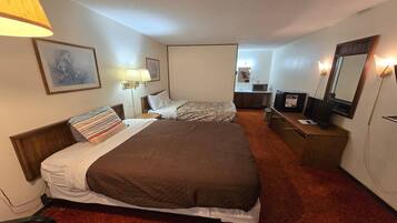 A hotel room with two beds, a desk, a chair, a TV, and a mirror.