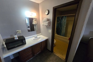 A bathroom with a sink, mirror, clock, and towels.