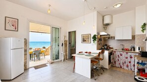 A kitchen with a view of the sea, a dining area, and a small bar area. - La Casa in Riva al Mare by Geco Vacation Rentals (Caucana)