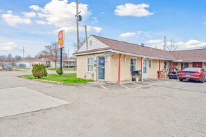 A small office building with a single entrance, a parking lot, and a red car parked in front.