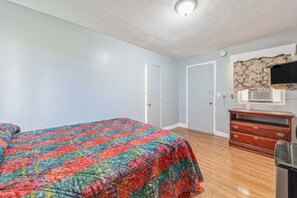 A bedroom with a bed, a dresser, a television, and a door.