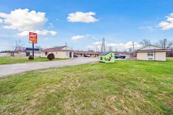 A motel with a prominent red sign, multiple single-story buildings, and a grassy parking area.