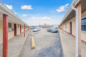 A row of motel rooms with a parking lot in between. - Queen Bed|Smoking|Flint MI (Flint MI)