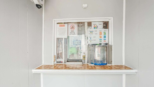 Een automaat met een bord waarop staat dat huisdieren niet toegestaan zijn, een mededeling over 10% korting bij contante betalingen en een prijslijst voor diverse artikelen.