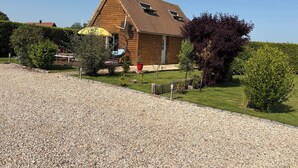 A wooden house with a gravel driveway, a yellow umbrella, and a red flower pot. - Chalet between land and sea (Ambrumesnil)