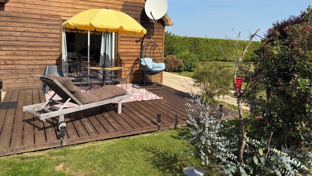 A wooden cabin with a deck, outdoor furniture, a hanging chair, and a satellite dish. - Chalet between land and sea (Ambrumesnil)