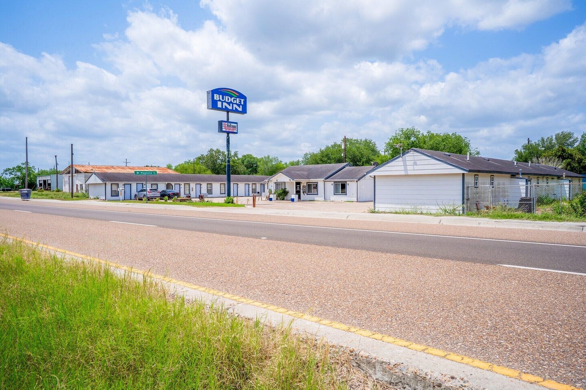 A Budget Inn motel with a sign, a road, and a grassy area.