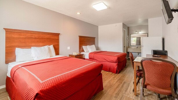 Een hotelkamer met twee bedden, een bureau, een stoel, een televisie en een badkamer in de achtergrond.