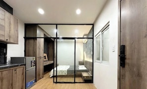 Una habitación compacta con kitchenette, una cama y una puerta corredera que da a otra habitación.