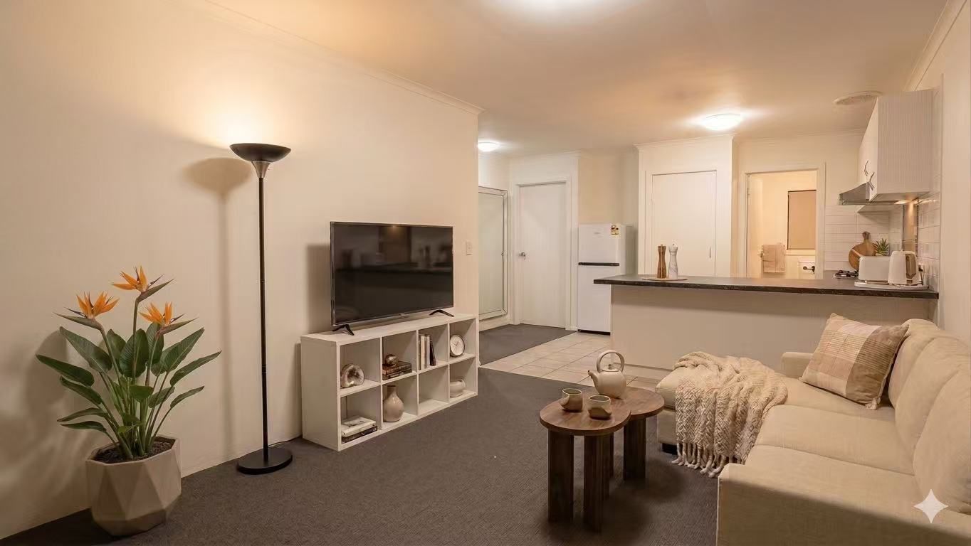 A living room with a TV, a sofa, a coffee table, a floor lamp, and a potted plant.