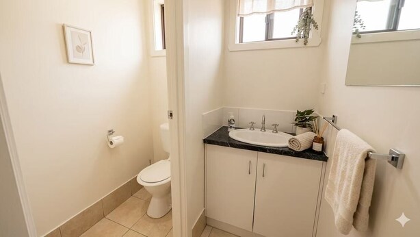 A bathroom with a toilet, sink, and mirror. - Cosy & stylish 2BR | Your home base in East Albury (East Albury)