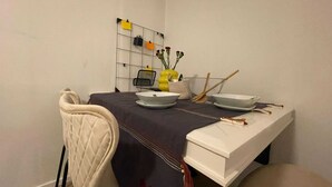 A dining area with a table set for two, a chair, a small vase with flowers, and a wall-mounted organizer with notes. - Pet Friendly Urban Escape in Antwerp (Antwerp)