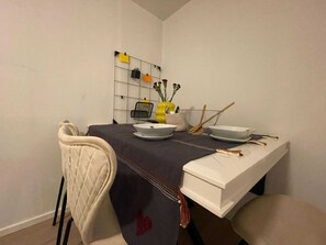 A dining area with a table set for two, a chair, a small vase with flowers, and a wall-mounted organizer with notes. - Pet Friendly Urban Escape in Antwerp (Antwerp)