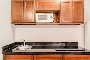 A kitchen with wooden cabinets, a microwave, a sink, and a stove.