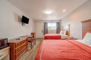 A hotel room with a bed, a desk, a chair, a TV, and a window with curtains.