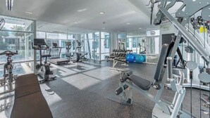 Une salle de sport moderne dotée de divers équipements d’exercice, de grandes fenêtres et d’un aménagement spacieux.