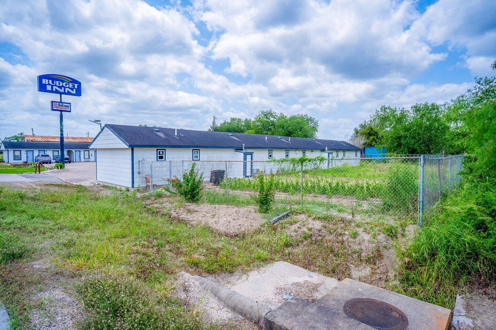 Un motel de la chaîne Budget Inn, doté d’un parking clôturé et d’un terrain herbeux.