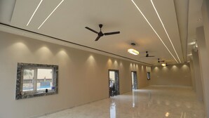 Un pasillo amplio con ventiladores de techo, iluminación empotrada y piso de mármol.