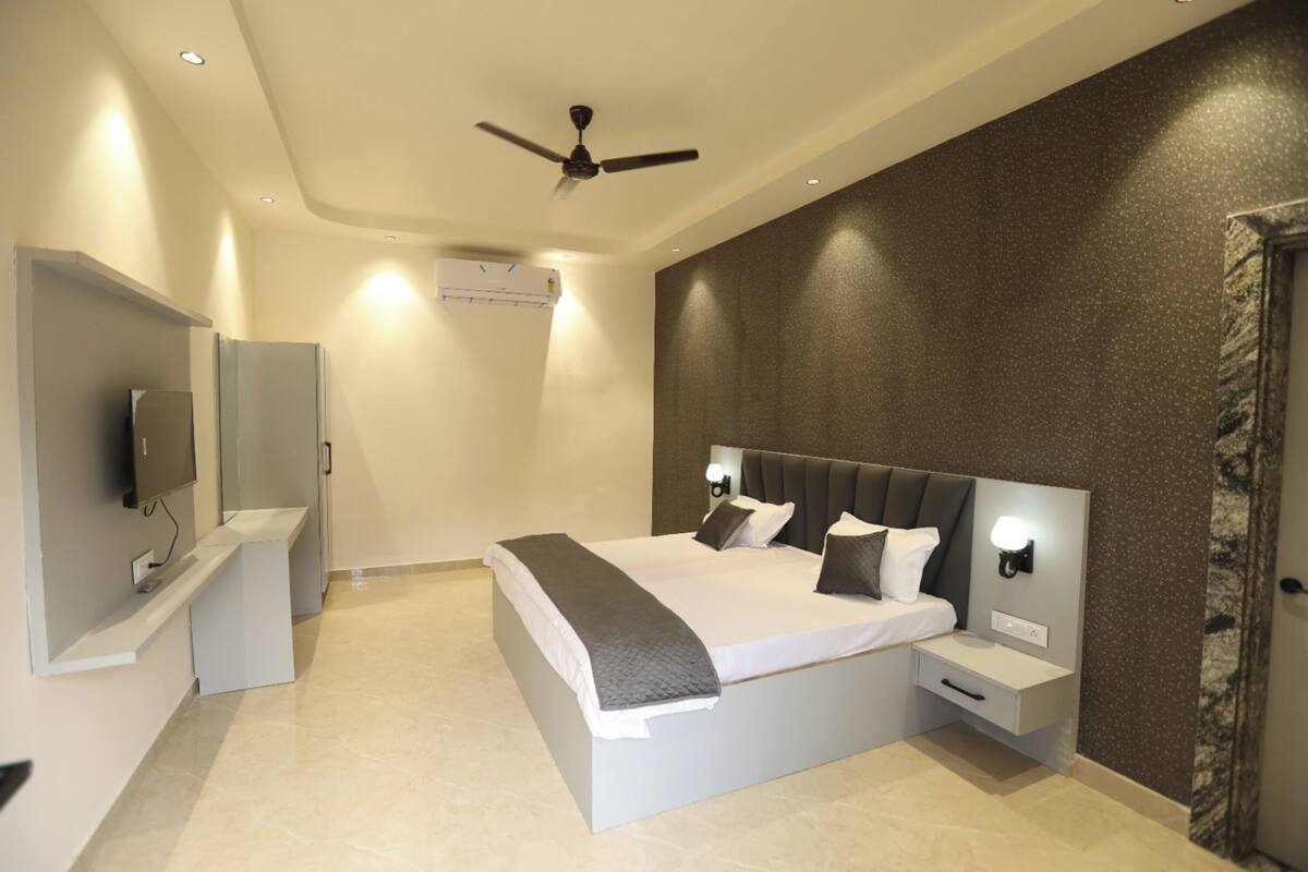 Un dormitorio moderno con una cama, mesitas de noche, un ventilador de techo y un televisor.